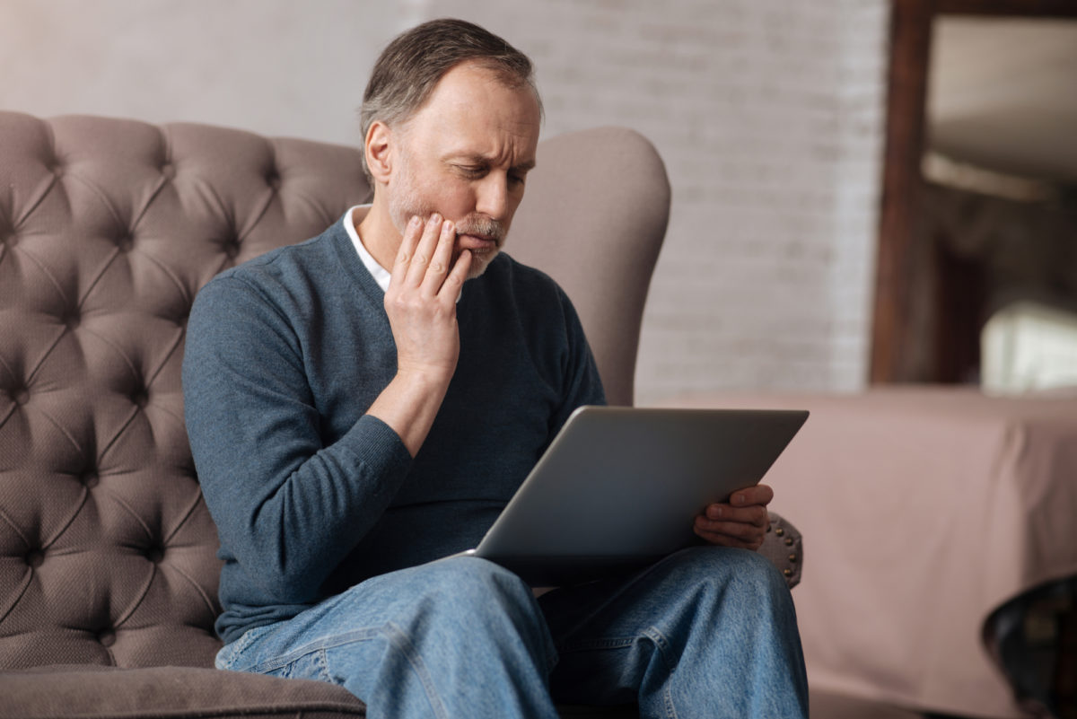 Person sitting at laptop searching the phrase ‘oral and maxillofacial surgeon near me’